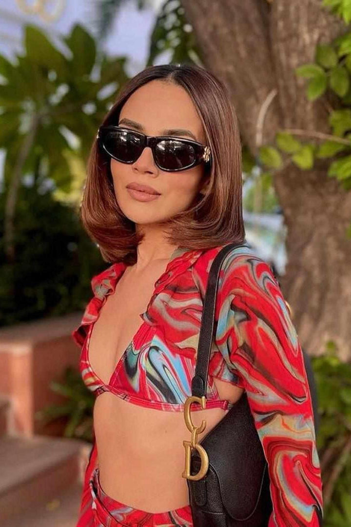 Woman wearing red printed cayenne wave ruffled sleeve top and ruched skirt and bikini top, swimwear for women, resort wear for ladies, sarong, izsi India