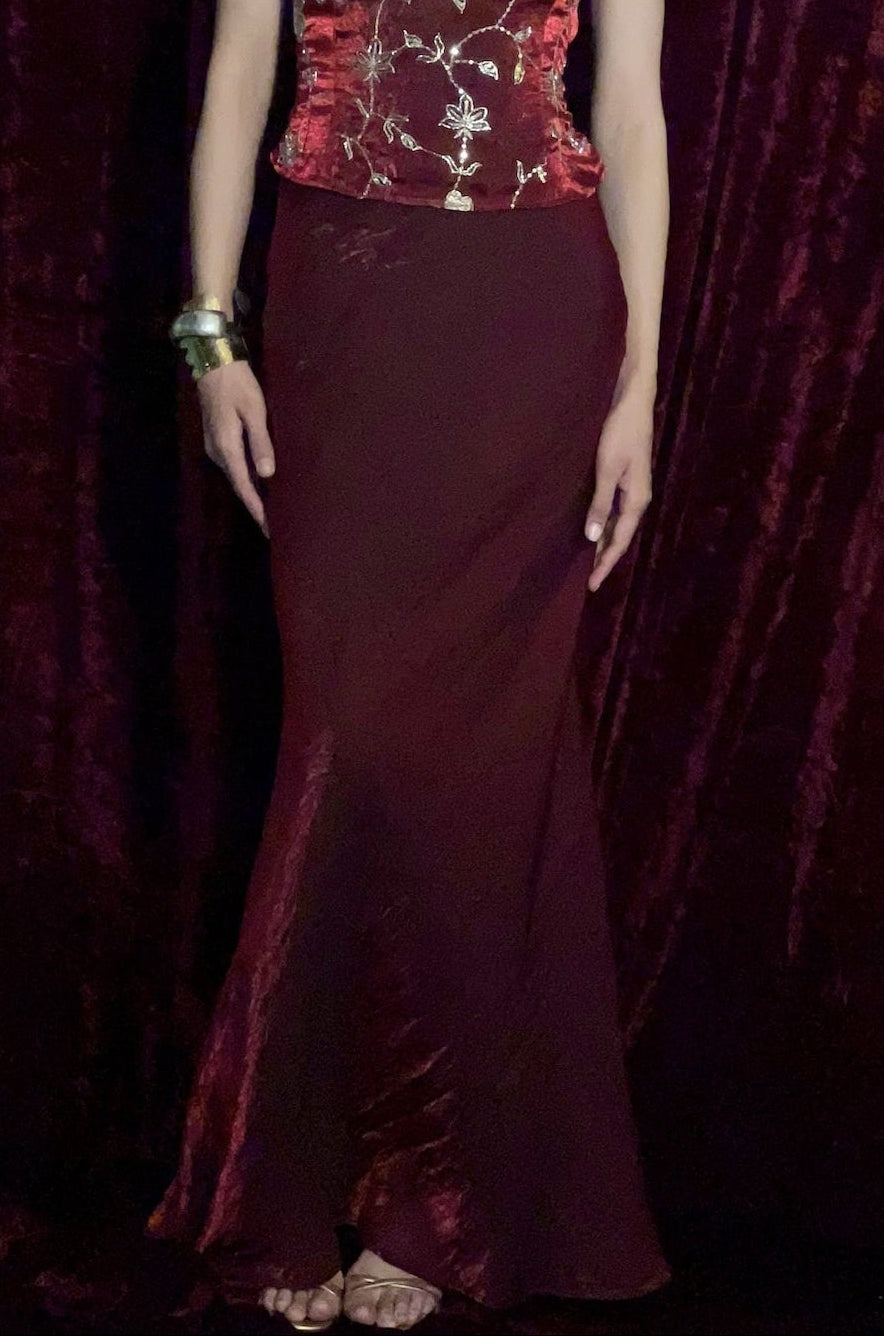 Woman wearing a burgundy evening gown against a dark red curtain